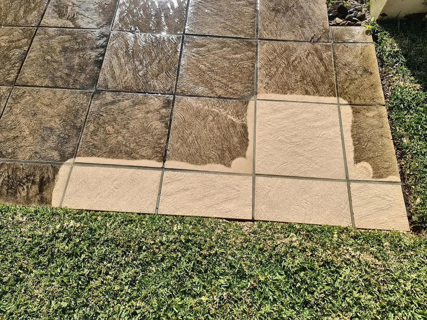 Pavers halfway through a pressure clean, with the clean section showing the true colour