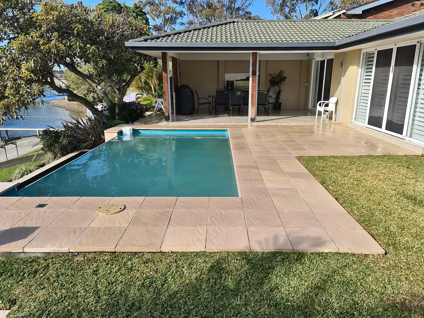 Pool, clean paving and a mown lawn in a backyard