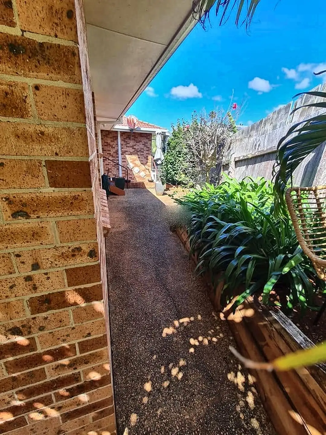 Narrow side path stained dark beside a brick house