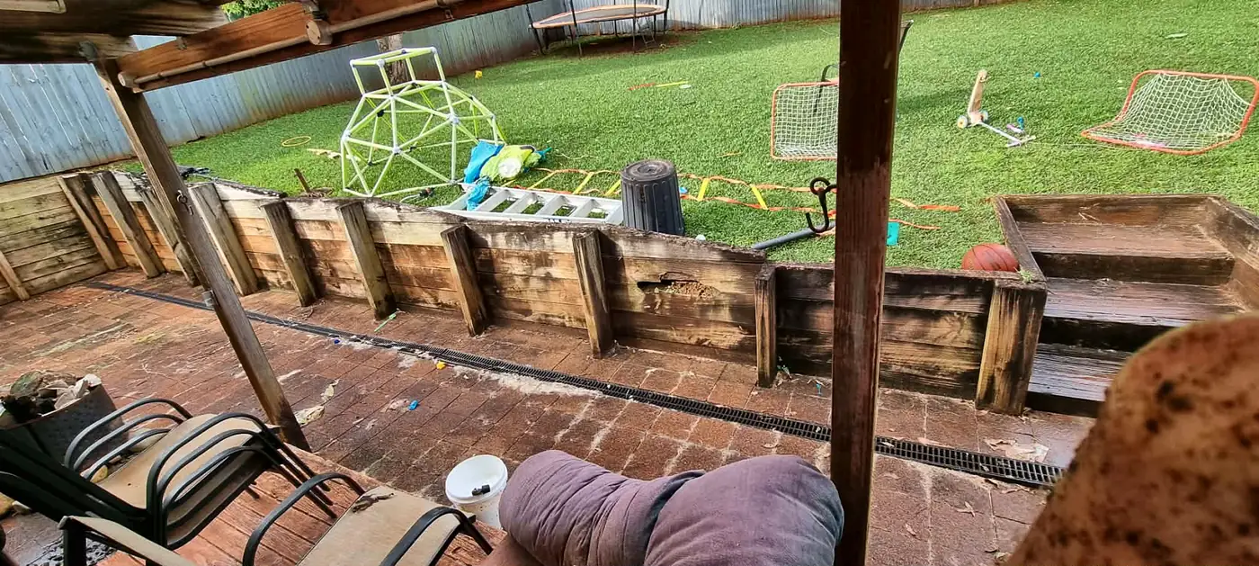 Timber retaining wall grey and weathered beside a paved patio
