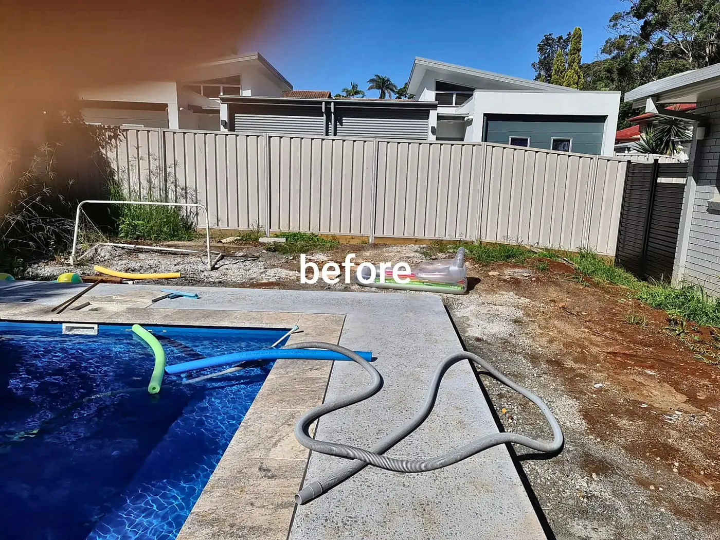 Backyard beside a pool before landscaping, with bare dirt and rubble