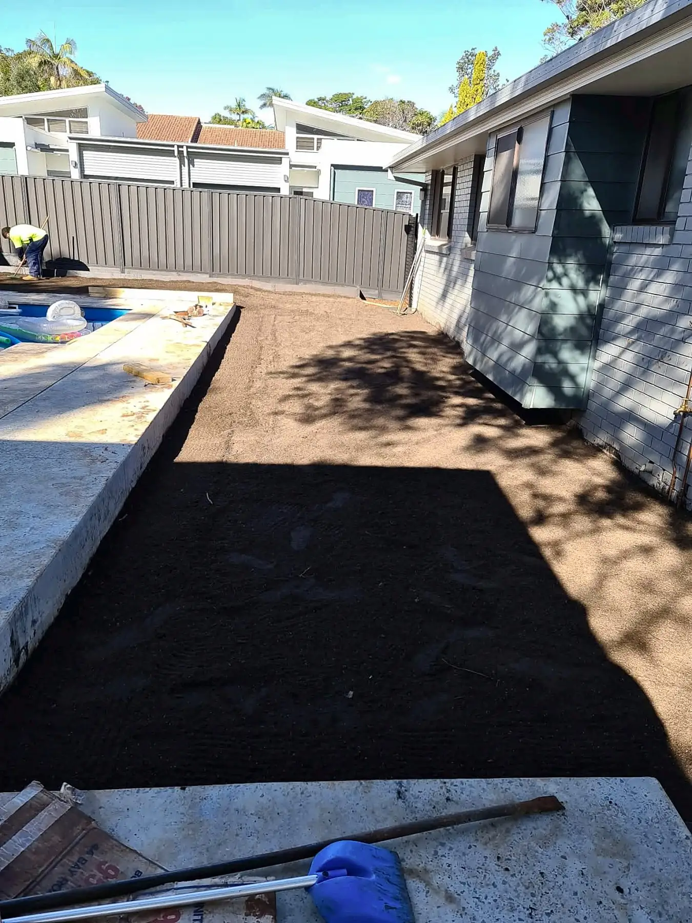 Prepared soil strip ready for turf beside a pool